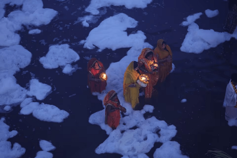 Devotees stand amidst the foam covering the Yamuna river in New Delhi, India, November 20, 2023. PHOTO: REUTERS